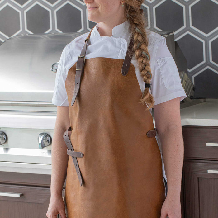 Lady wearing a Messermeister brown leather apron in a kitchen setting