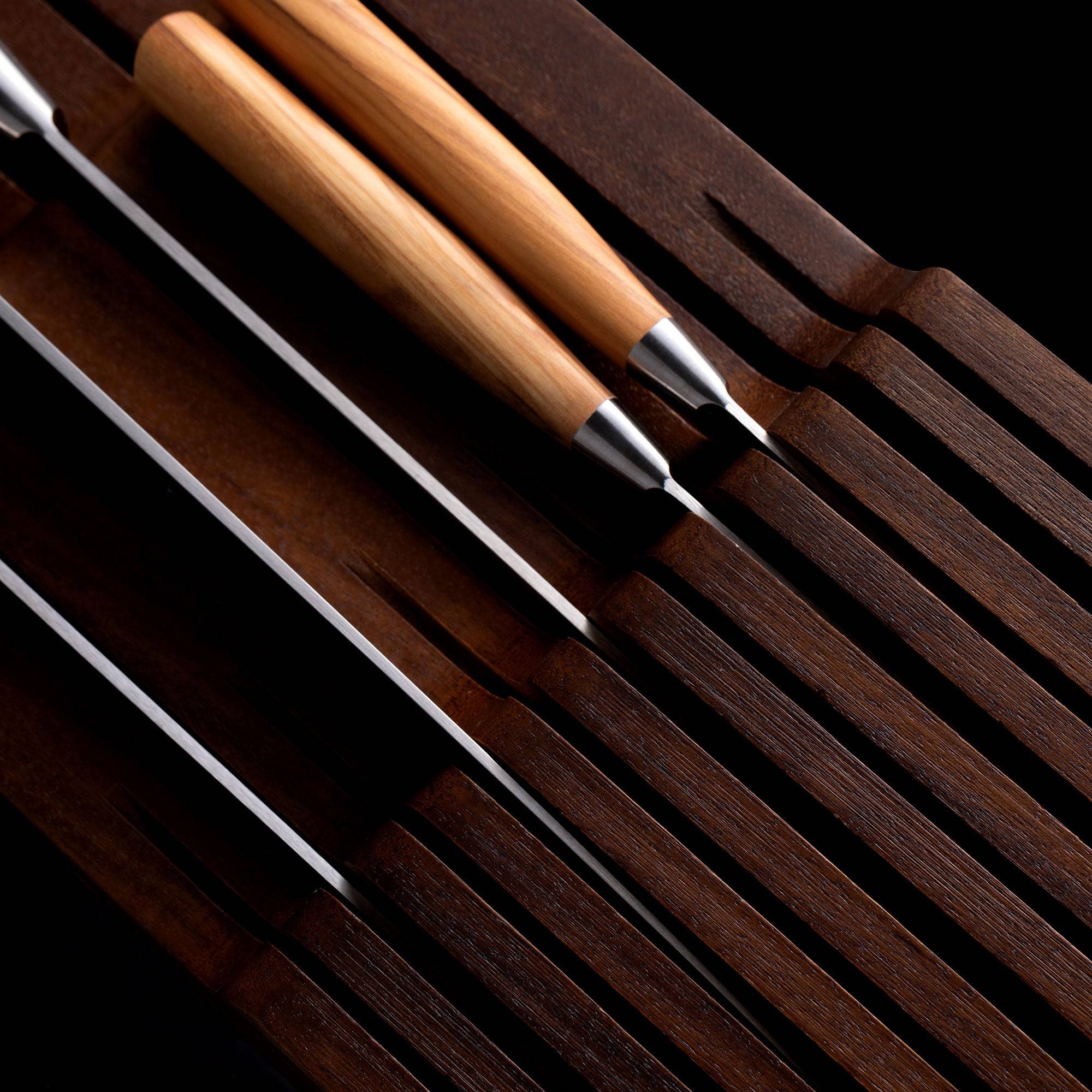 Messermeister 11 Slot Contemporary Acacia In-Drawer Knife Holder shows a close up of 5 Olive Wood knives situated within the slots. Knife handles pointing to the left.
