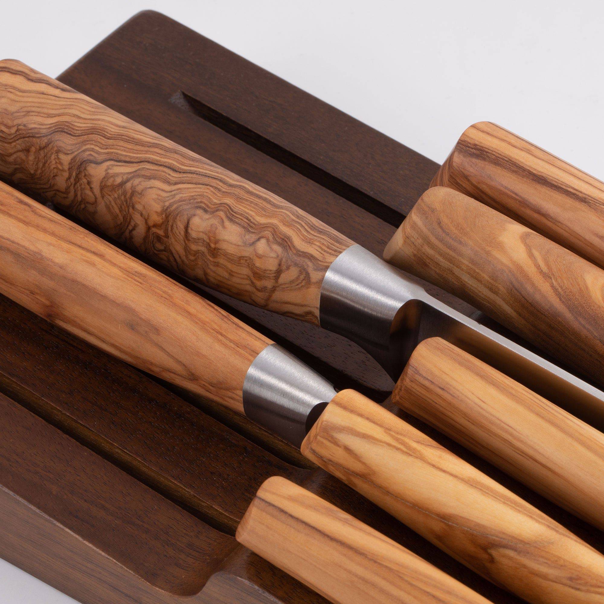 Messermeister 11 Slot Contemporary Acacia In-Drawer Knife Holder shows a close up of 7 Olive Wood knives situated within the slots.
