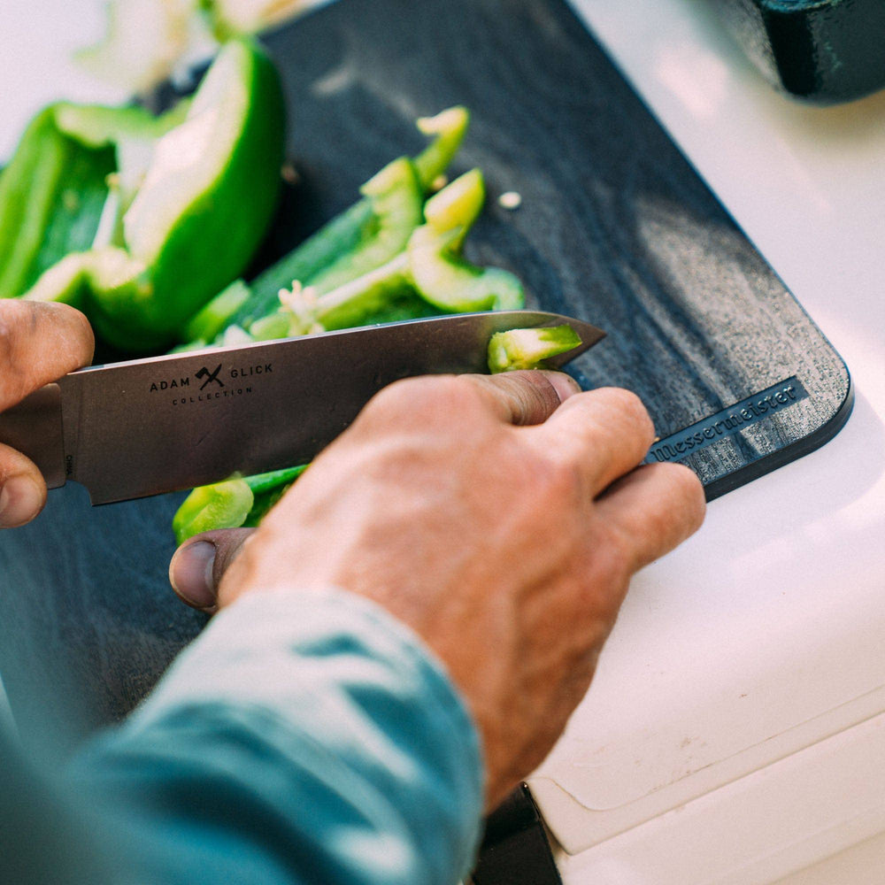 Photo of person chopping vegetables on the faux wood cutting board using the folding 6 inch chef's knife