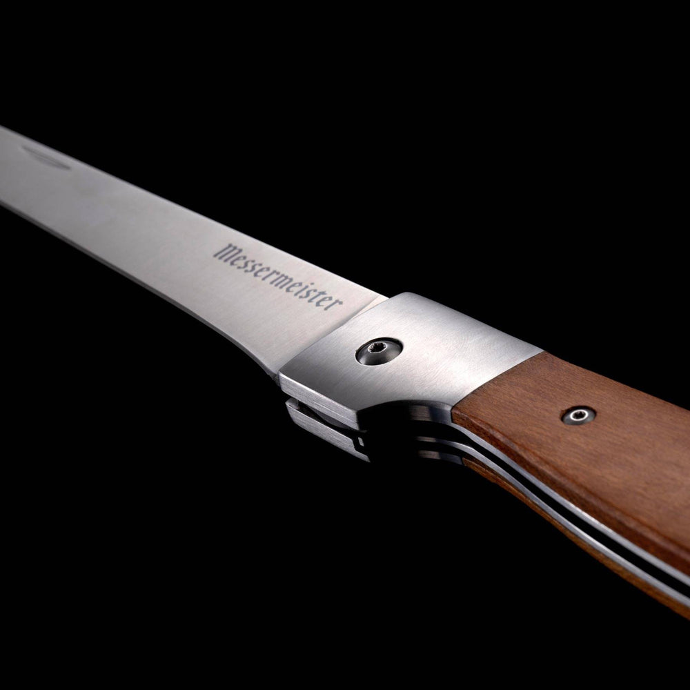 A close up view of the blade and maple handle on the Messermeister Adventure Chef Folding 6 inch Fillet Knife 