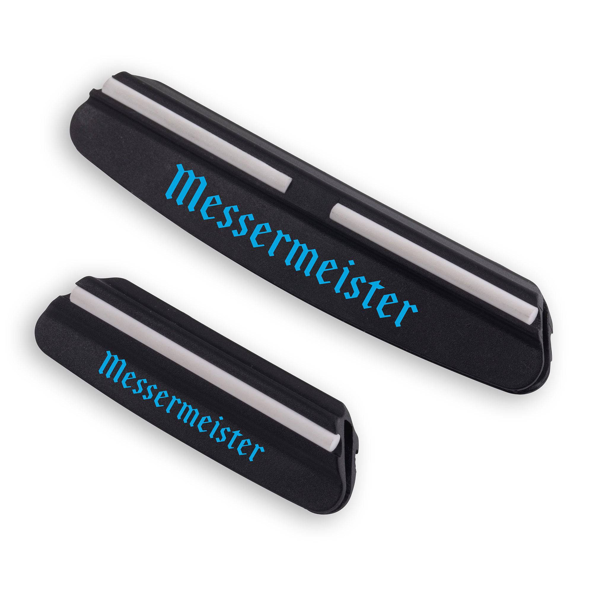 2 Messermeister Angle Guides. Both black elongated rectangles with a white rubber along the top and blue MESSERMEISTER words along the body. An opening in the plastic along the bottom. Top guard is larger is size.