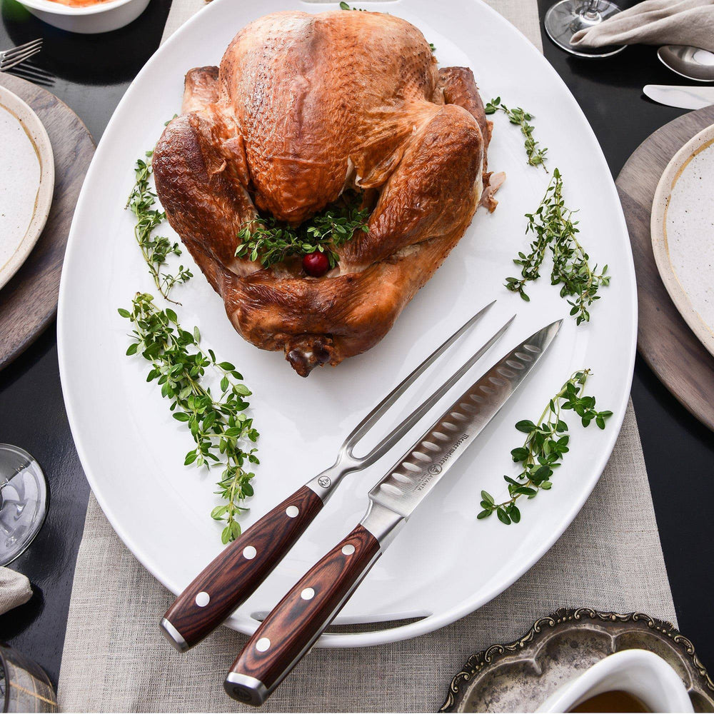 Messermeister Avanta pakkawood 2-piece kullens carving set next to cooked chicken on white serving plate