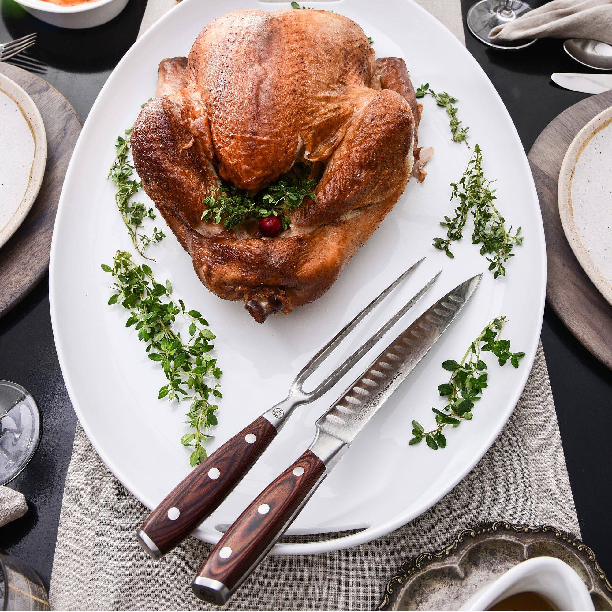 Messermeister Avanta pakkawood 2-piece kullens carving set next to cooked chicken on white serving plate