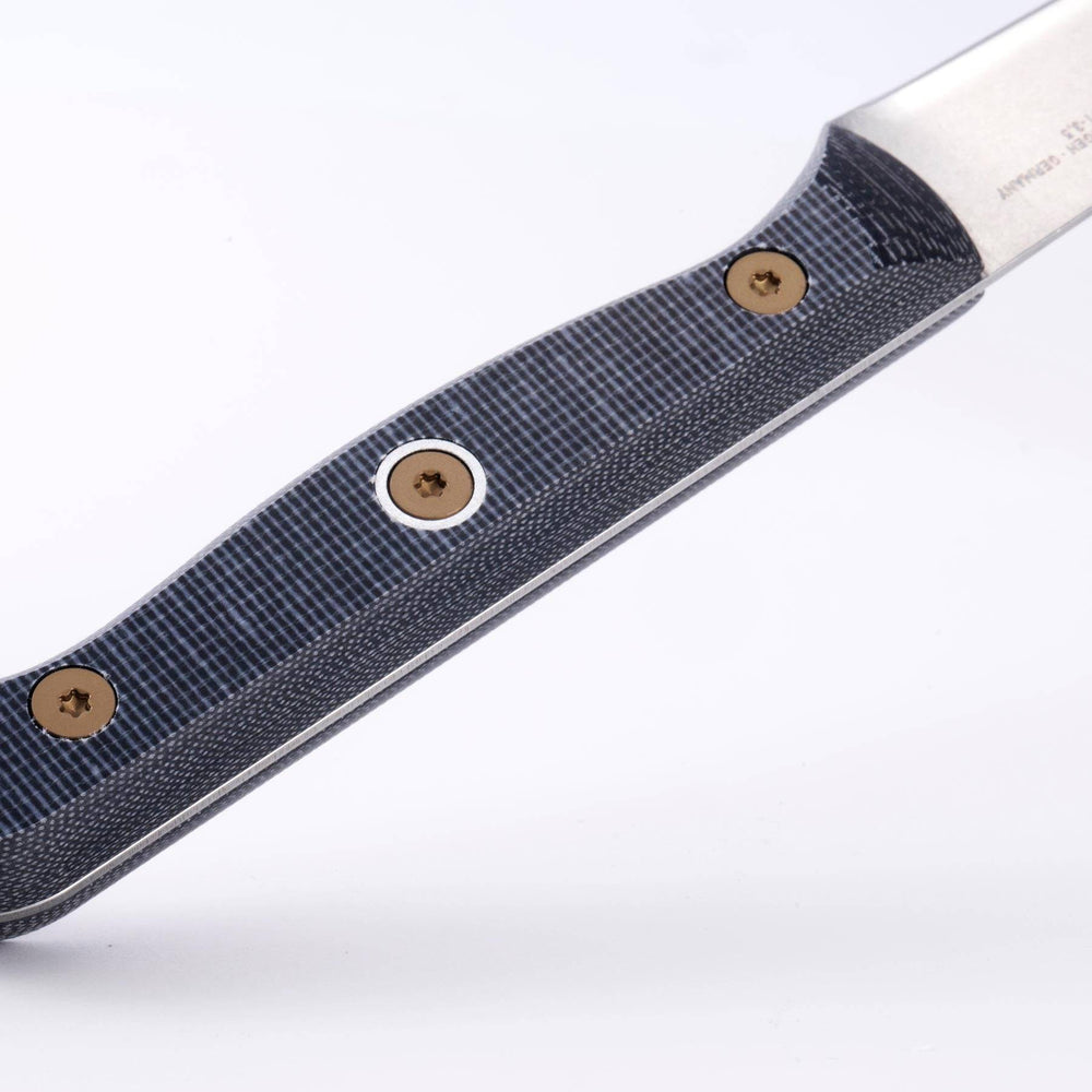 Close-up of the handle on a Messermeister Custom 3.5-inch paring knife, featuring a textured linen micarta grip with visible layered pattern, ergonomic contour, and riveted modular design, highlighting the durable, non-slip surface