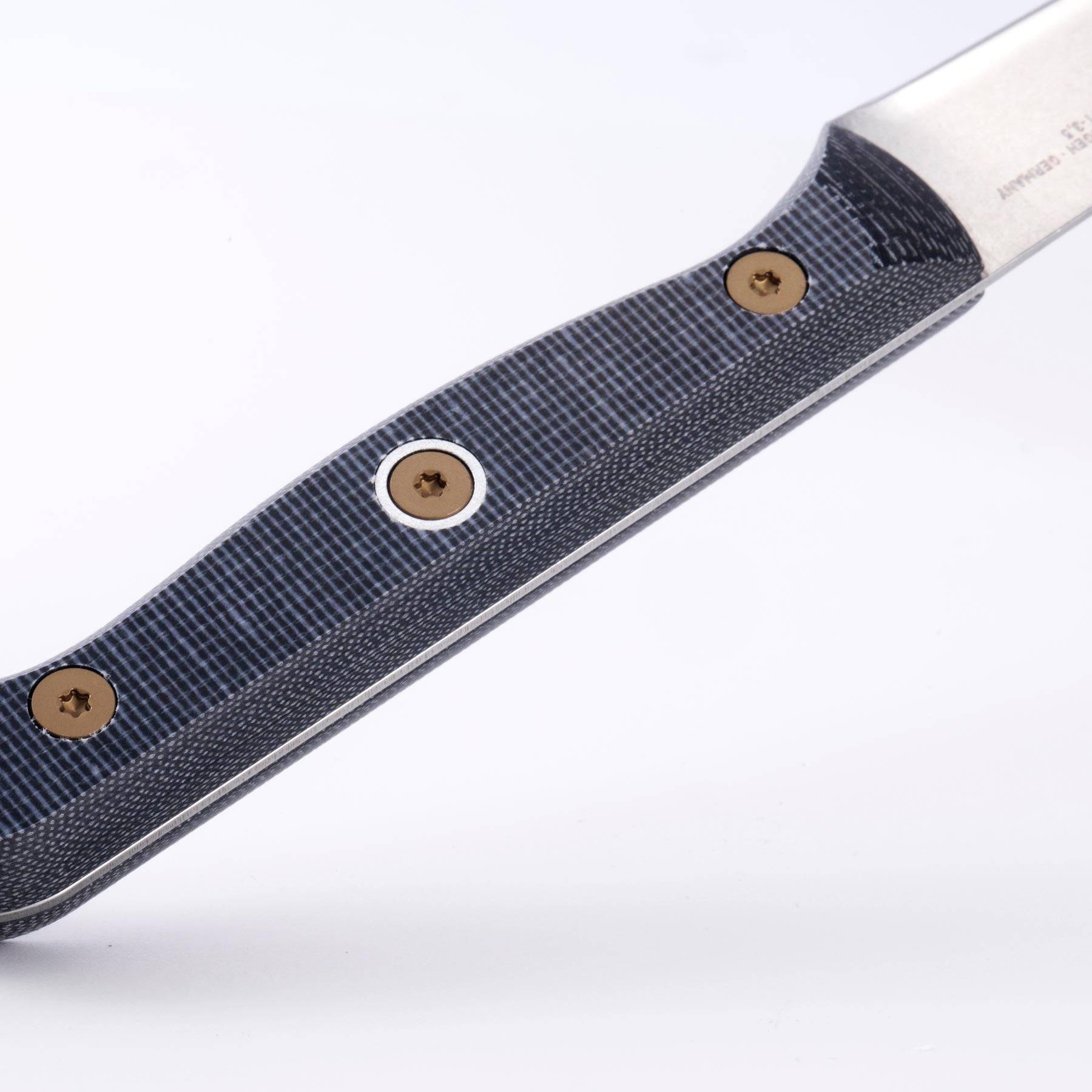 Close-up of the handle on a Messermeister Custom 3.5-inch paring knife, featuring a textured linen micarta grip with visible layered pattern, ergonomic contour, and riveted modular design, highlighting the durable, non-slip surface