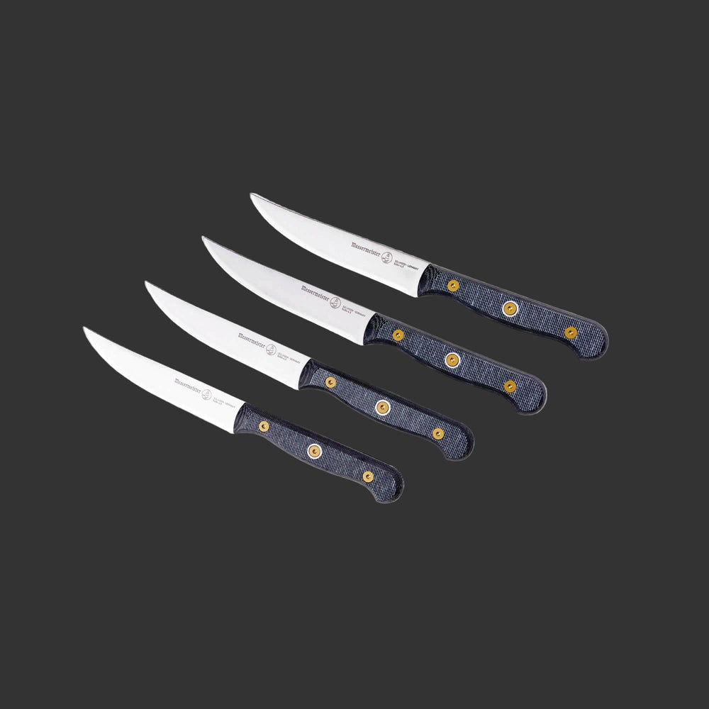 Angled upward view of a four-piece Messermeister Custom steak knife set with 5-inch blades highlighting the stainless steel blades, sharp cutting edges, and ergonomic modular handles with textured linen micarta handles