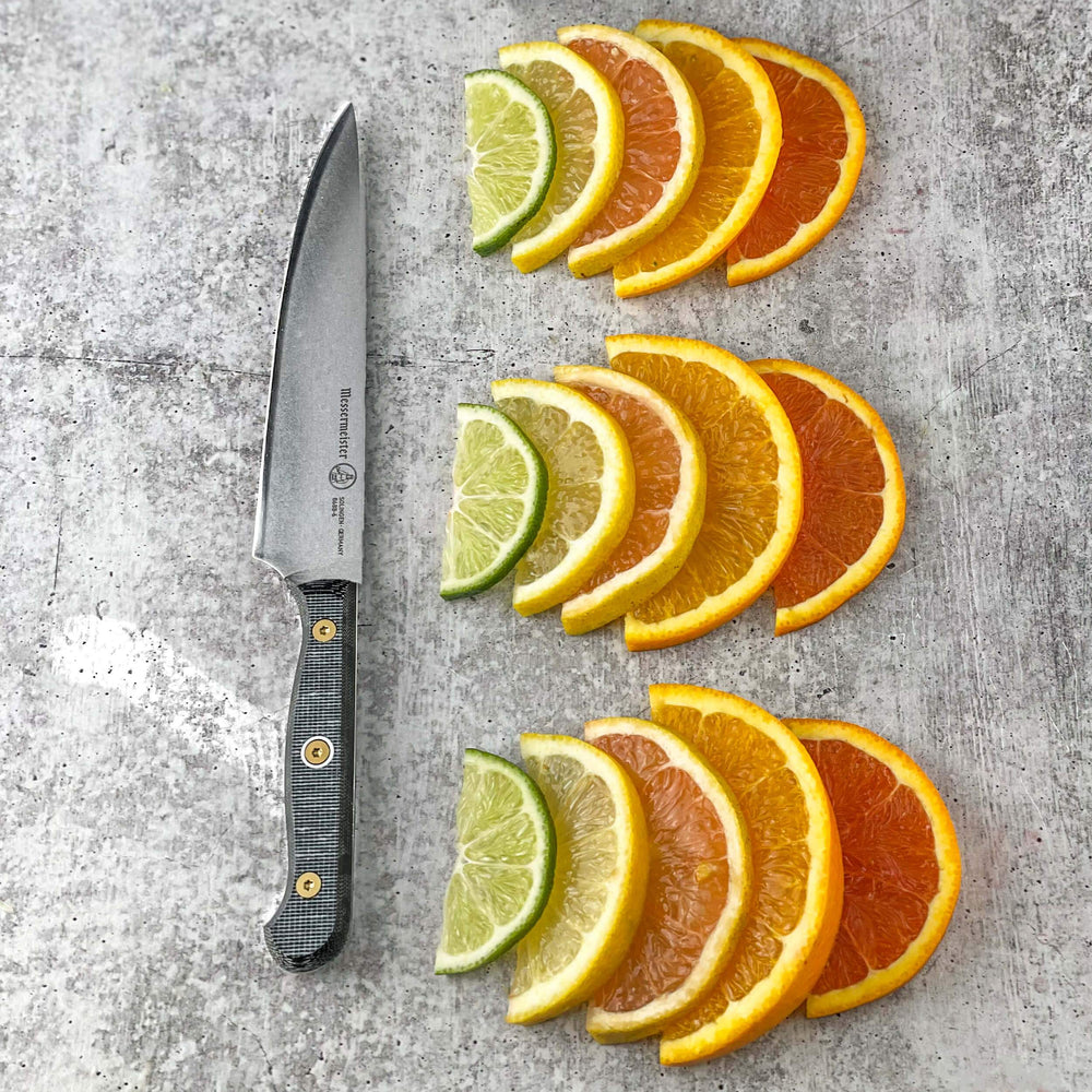 Messermeister Custom 6-inch utility knife next to neatly lined citrus wedges on a gray table