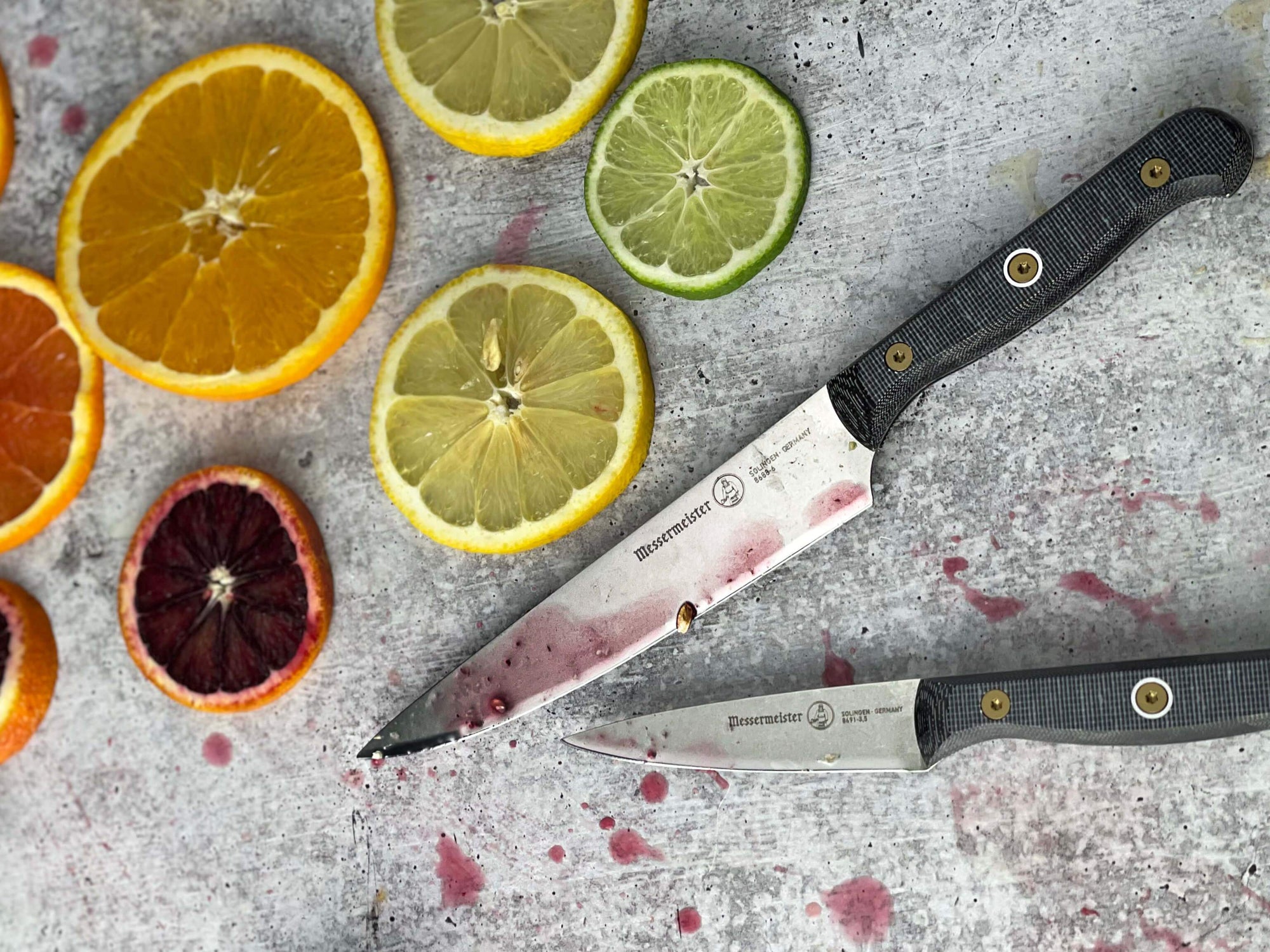 Messermeister Custom 6-inch utility knife and paring knife with fresh citrus rounds on gray table