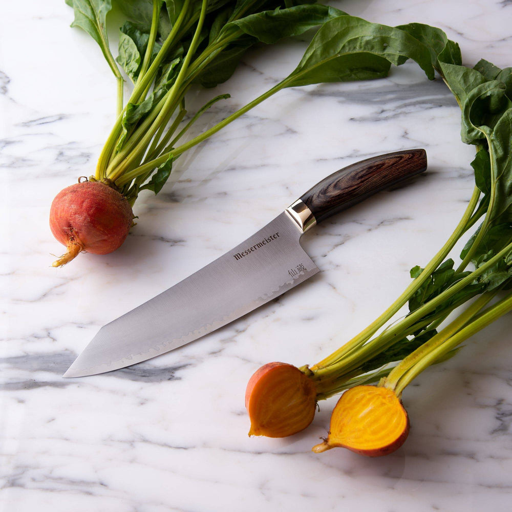 Kawashima 8 inch chef's knife with san mai steel blade with gold bolster and walnut pakkawood handle on a marble countertop next to some beets