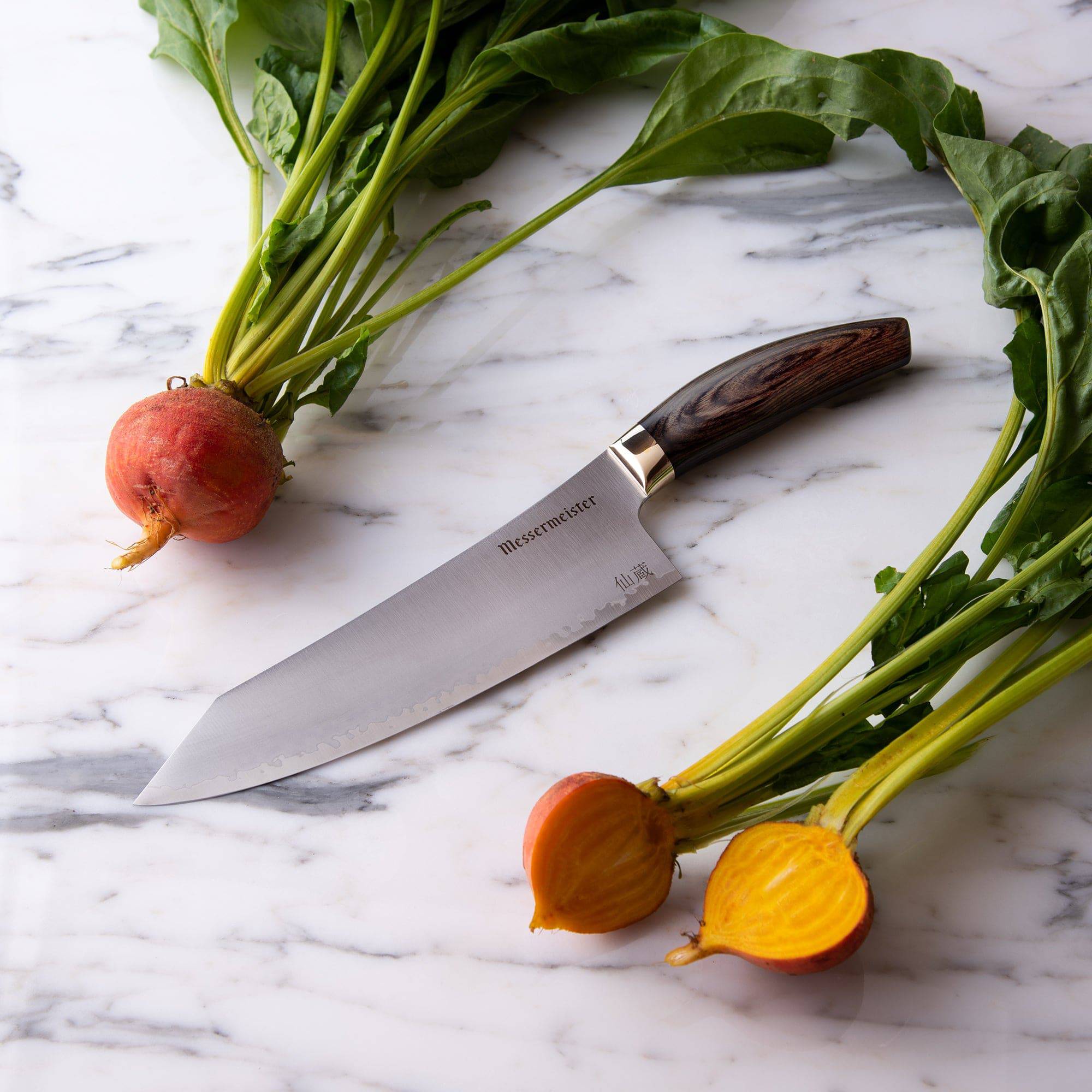 Kawashima 8 inch chef's knife with san mai steel blade with gold bolster and walnut pakkawood handle on a marble countertop next to some beets