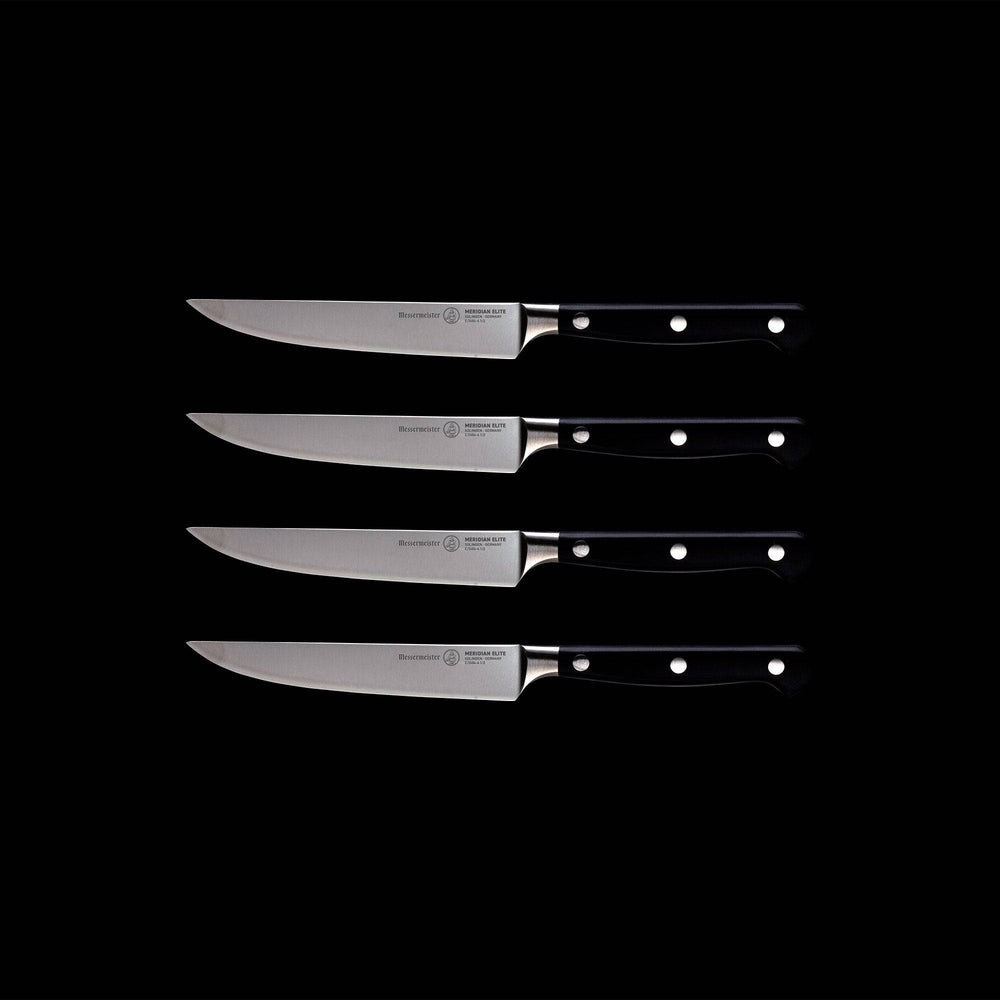 A set of four Meridian Elite fine edge steak knives with triple rivet black handles and stainless steel blades full view pointing left