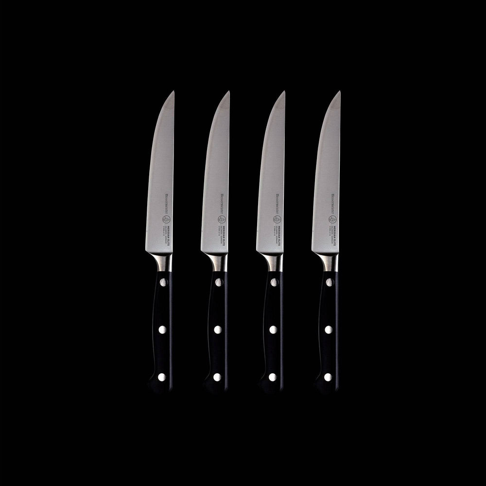 A set of four Meridian Elite fine edge steak knives with triple rivet black handles and stainless steel blades full view pointing up