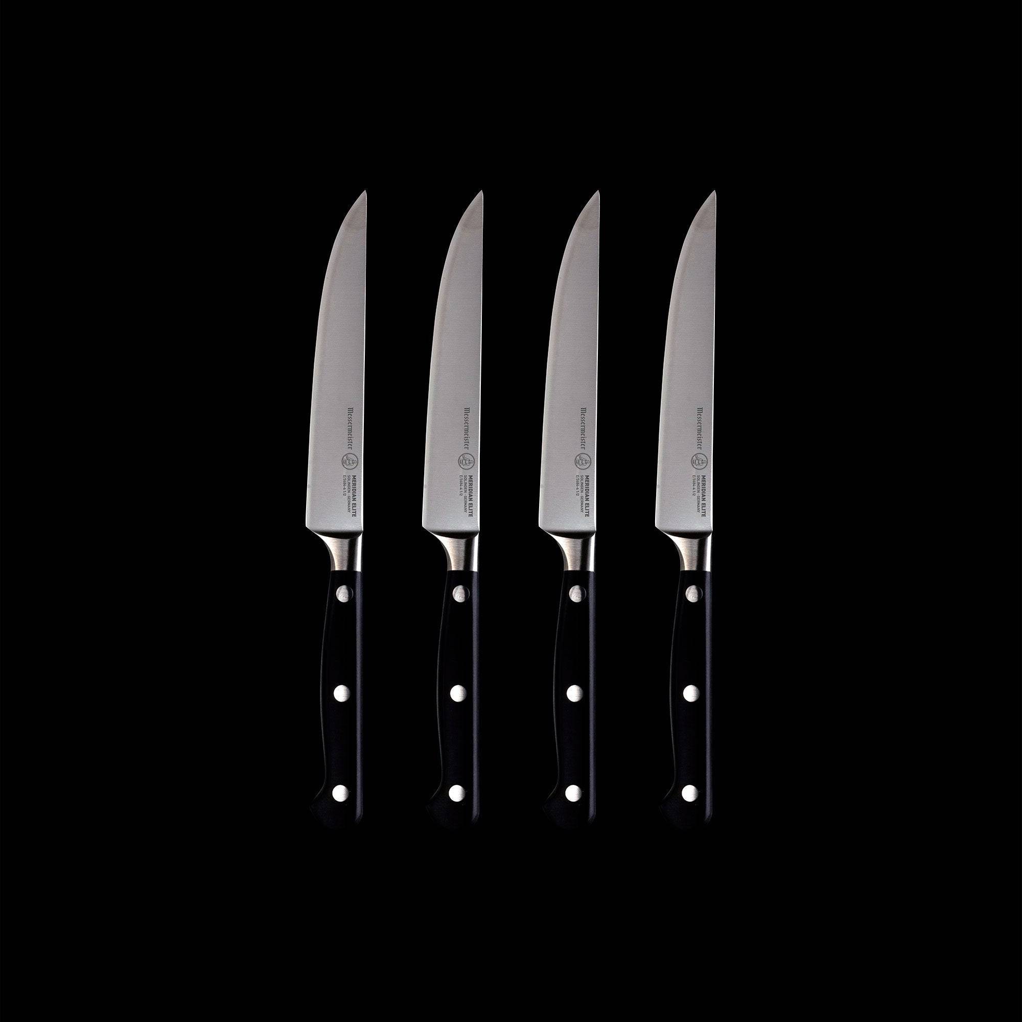 A set of four Meridian Elite fine edge steak knives with triple rivet black handles and stainless steel blades full view pointing up