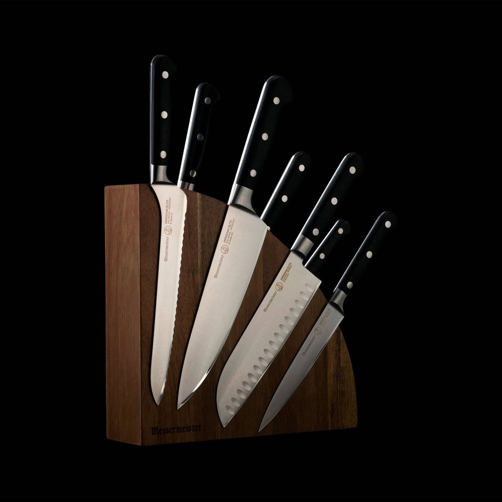 Messermeister Meridian Elite Magnet Block Set - 8 Piece - side view with Bread, Chef's, Santoku, and Utility knife showing. Other knife handles show in the background. Mounted on the quarter circle magnetic block.