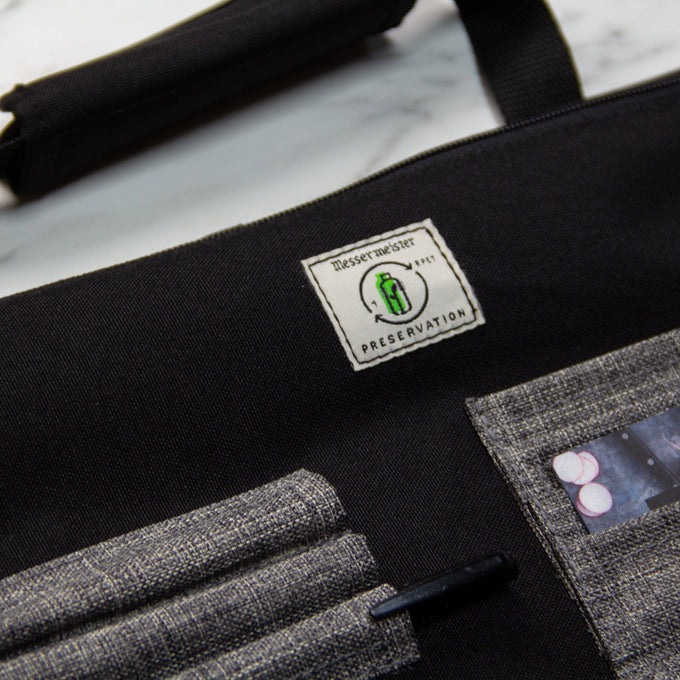Close-up of Messermeister Preservation 12 Pocket Knife Bag in Black highlighting recycled material label, durable eco-friendly fabric, and reinforced stitching