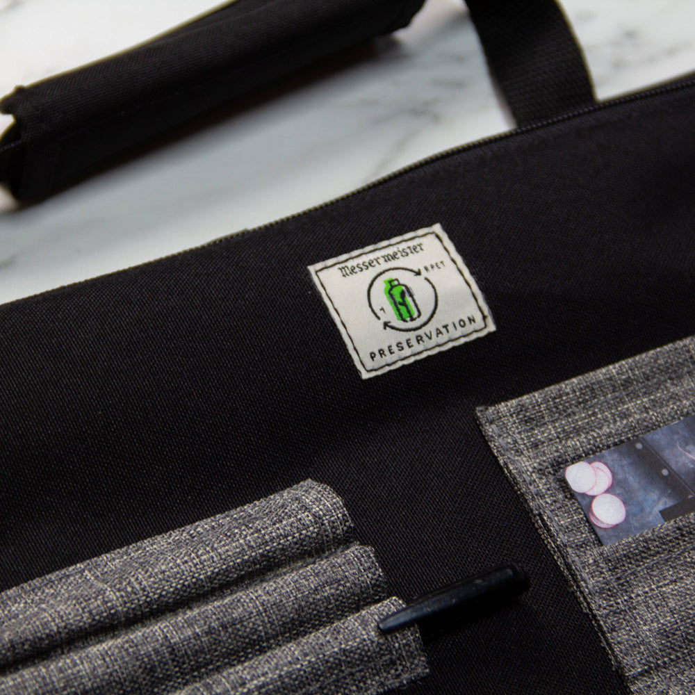 Close-up of Messermeister Preservation 8 Pocket Knife Bag in Black highlighting recycled material label, durable eco-friendly fabric, and reinforced stitching