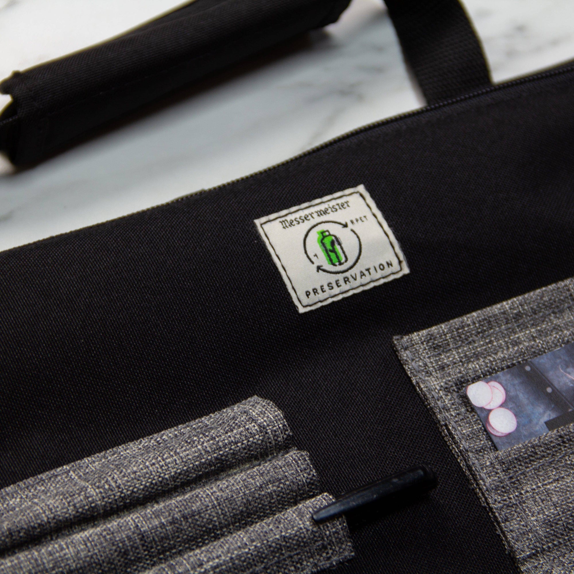 Close-up of Messermeister Preservation 8 Pocket Knife Bag in Black highlighting recycled material label, durable eco-friendly fabric, and reinforced stitching