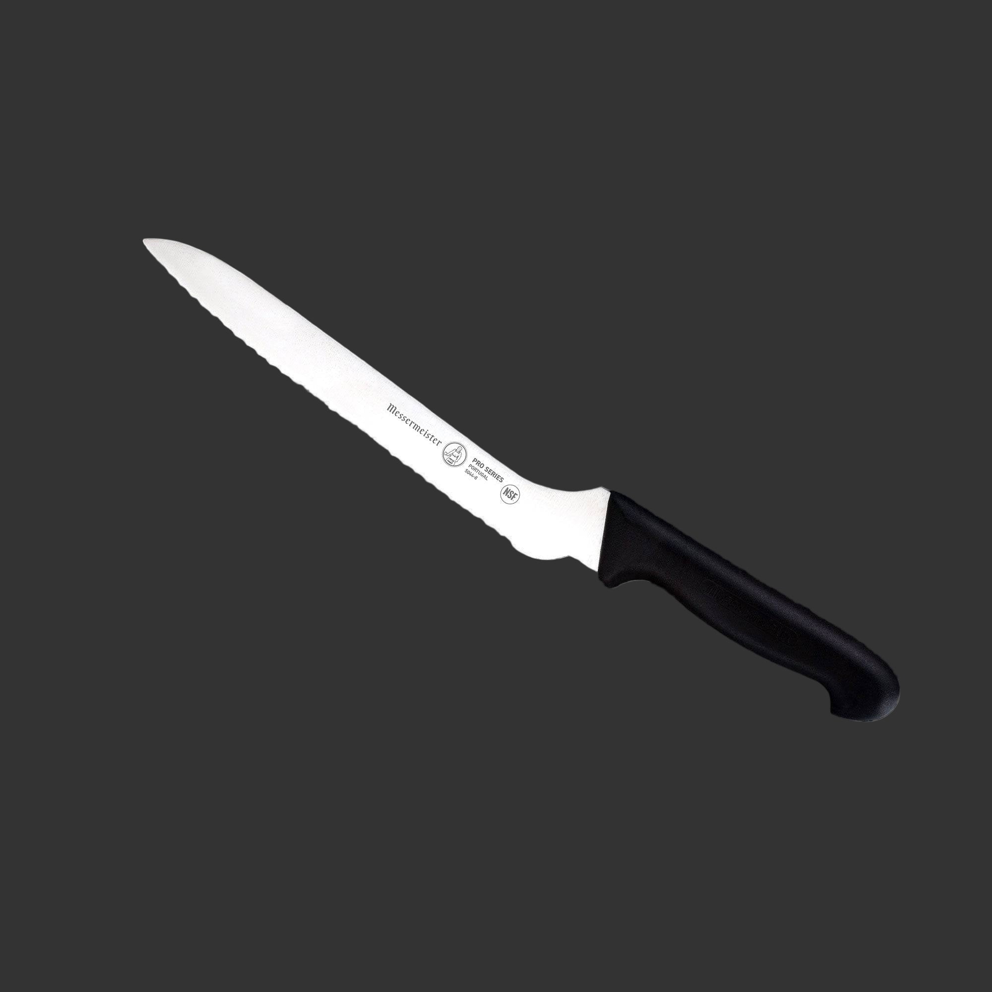 Angled view of Messermeister Pro Series 10-inch scalloped baker’s knife with serrated blade and black ergonomic handle
