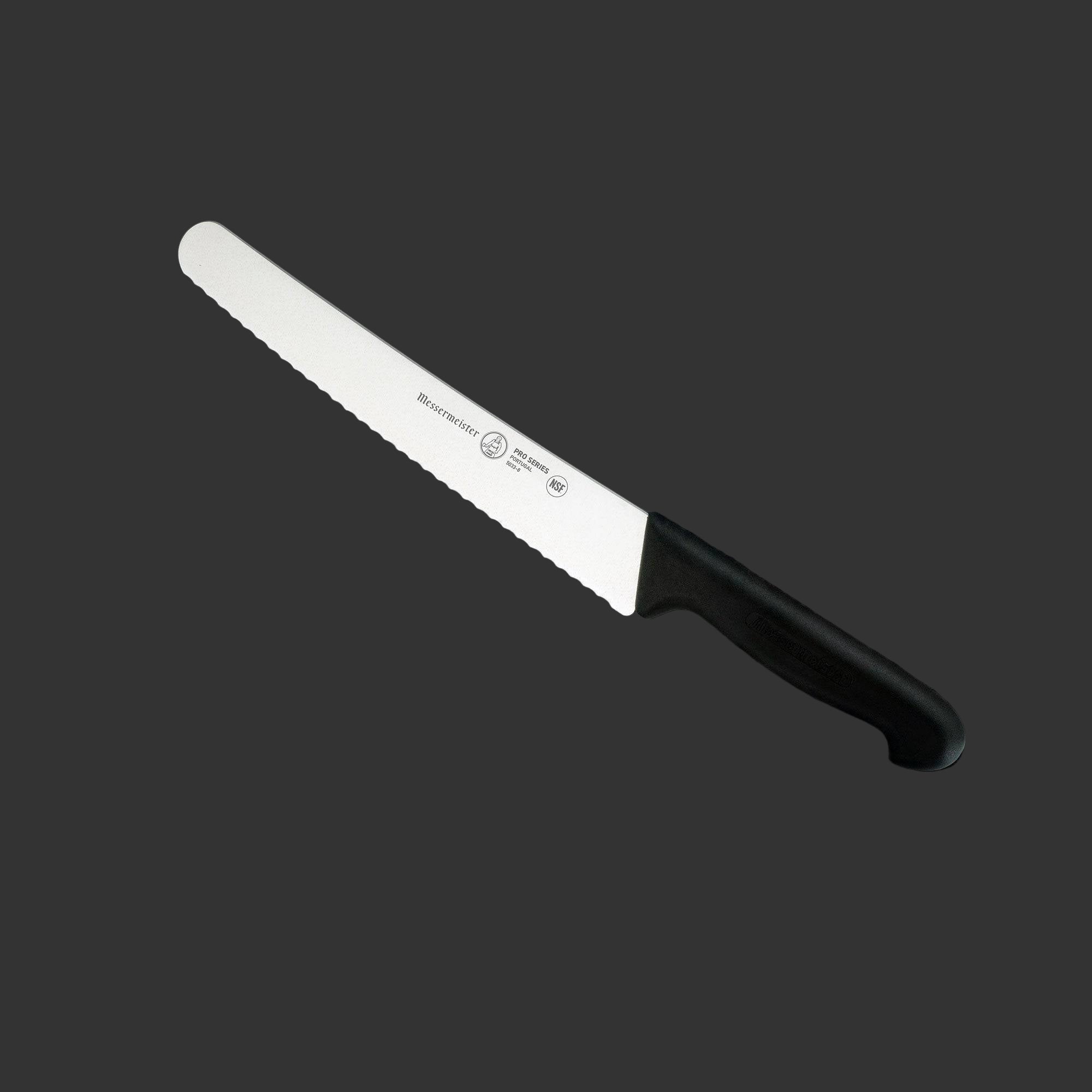 Angled view of Messermeister Pro Series 10-inch scalloped baker’s knife showing serrated stainless steel blade and ergonomic black polyfibre non-slip handle