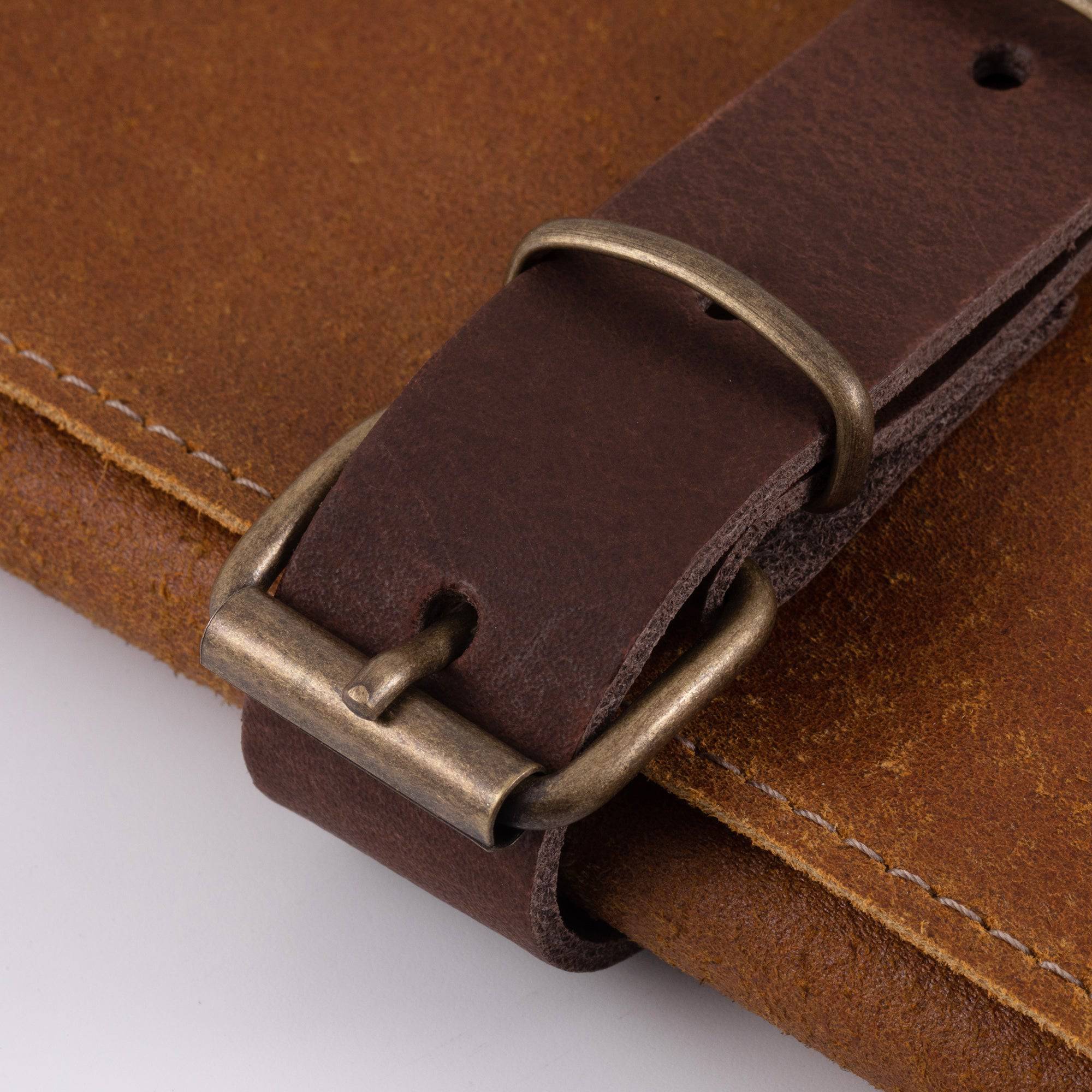 Close-up of the buckle closures on the Messermeister Vintage Leather 7 Pocket Knife Roll in amber brown, highlighting premium full-grain leather straps, brushed metal buckles, reinforced stitching, and handcrafted detailing for secure knife storage and transport