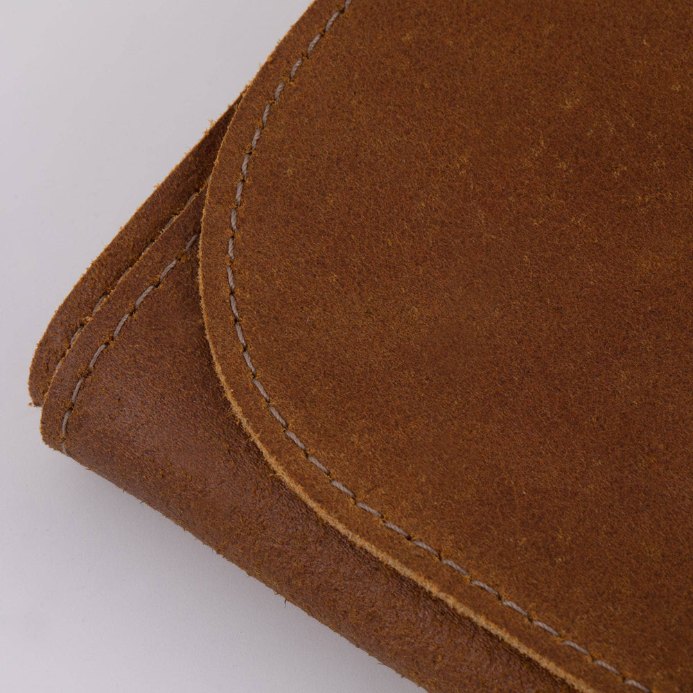 Close-up of the stitching on the Messermeister Vintage Leather 7 Pocket Knife Roll in amber brown, showcasing detailed handcrafted seams, reinforced construction, premium full-grain leather texture, and durable craftsmanship designed for long-lasting culinary tool storage