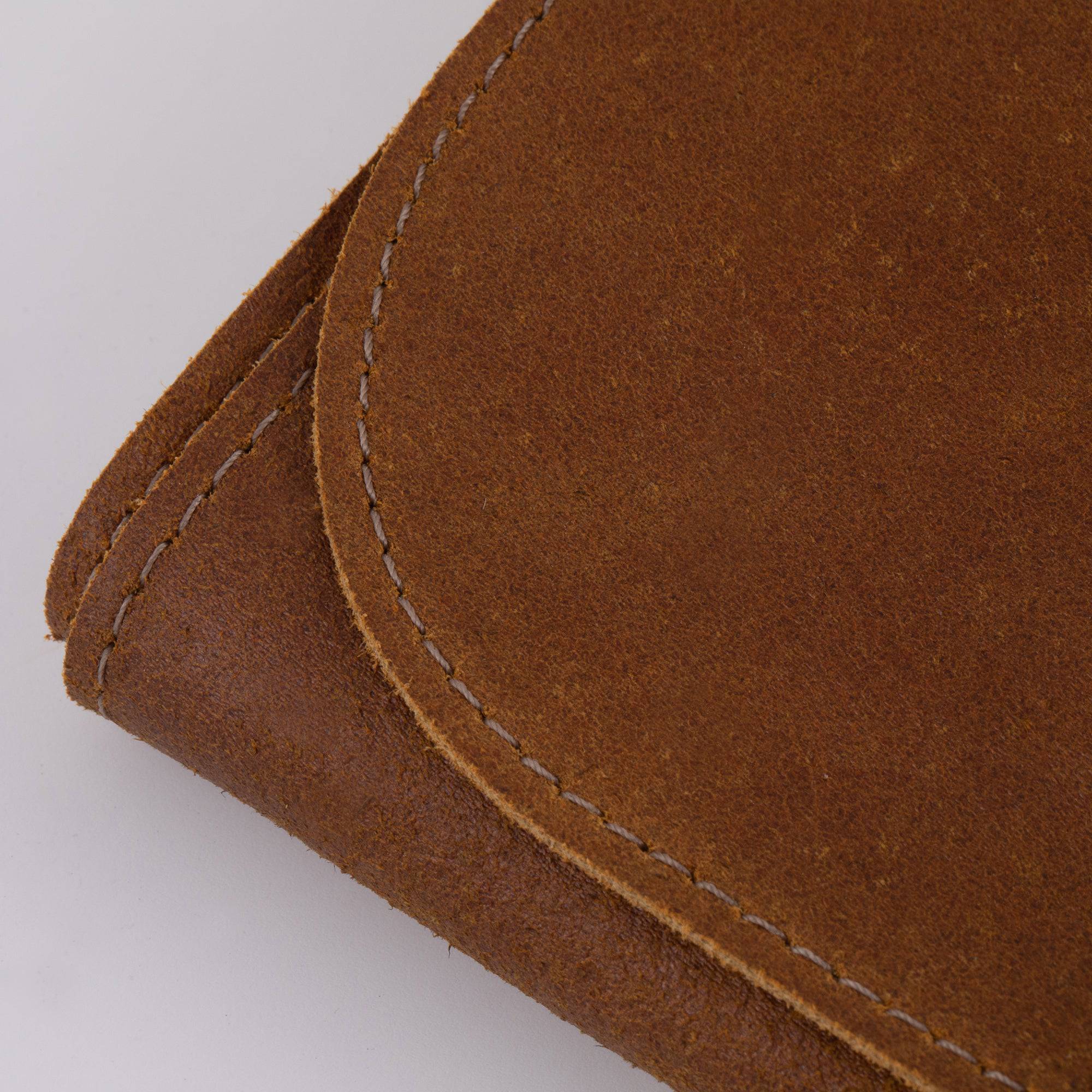 Close-up of the stitching on the Messermeister Vintage Leather 7 Pocket Knife Roll in amber brown, showcasing detailed handcrafted seams, reinforced construction, premium full-grain leather texture, and durable craftsmanship designed for long-lasting culinary tool storage