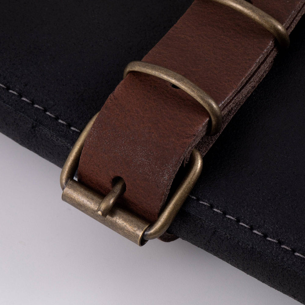 Close-up of the buckle closures on the Messermeister Vintage Leather 7 Pocket Knife Roll in black, showcasing premium full-grain leather straps, brushed metal buckles, reinforced stitching, and handcrafted detailing for secure knife storage and transport
