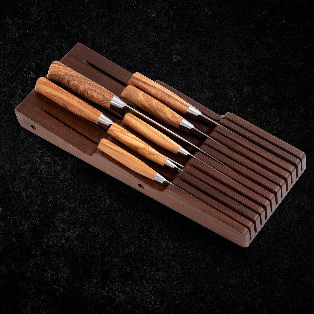 Messermeister 11 Slot Contemporary Acacia In-Drawer Knife Holder shows 7 Olive Wood knives stored within the slots on a black stone background.